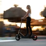 Woman enjoying an evening ride on an electric scooter with motion blur capturing speed and excitement.
