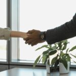 Professional handshake between two colleagues in modern office.